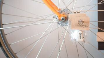 A bicycle wheel with an orange frame and a small package attached to the hub.