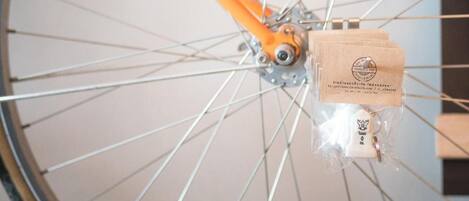 A bicycle wheel with an orange frame and a small package attached to the hub.