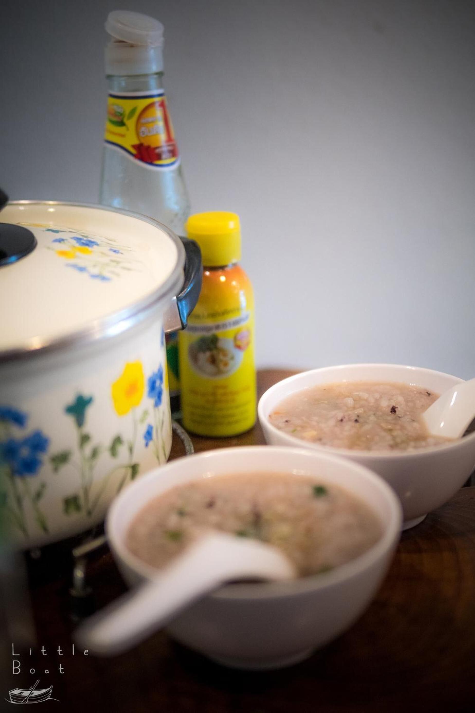 A kitchen setting with a pot, a bottle, and two bowls of soup.