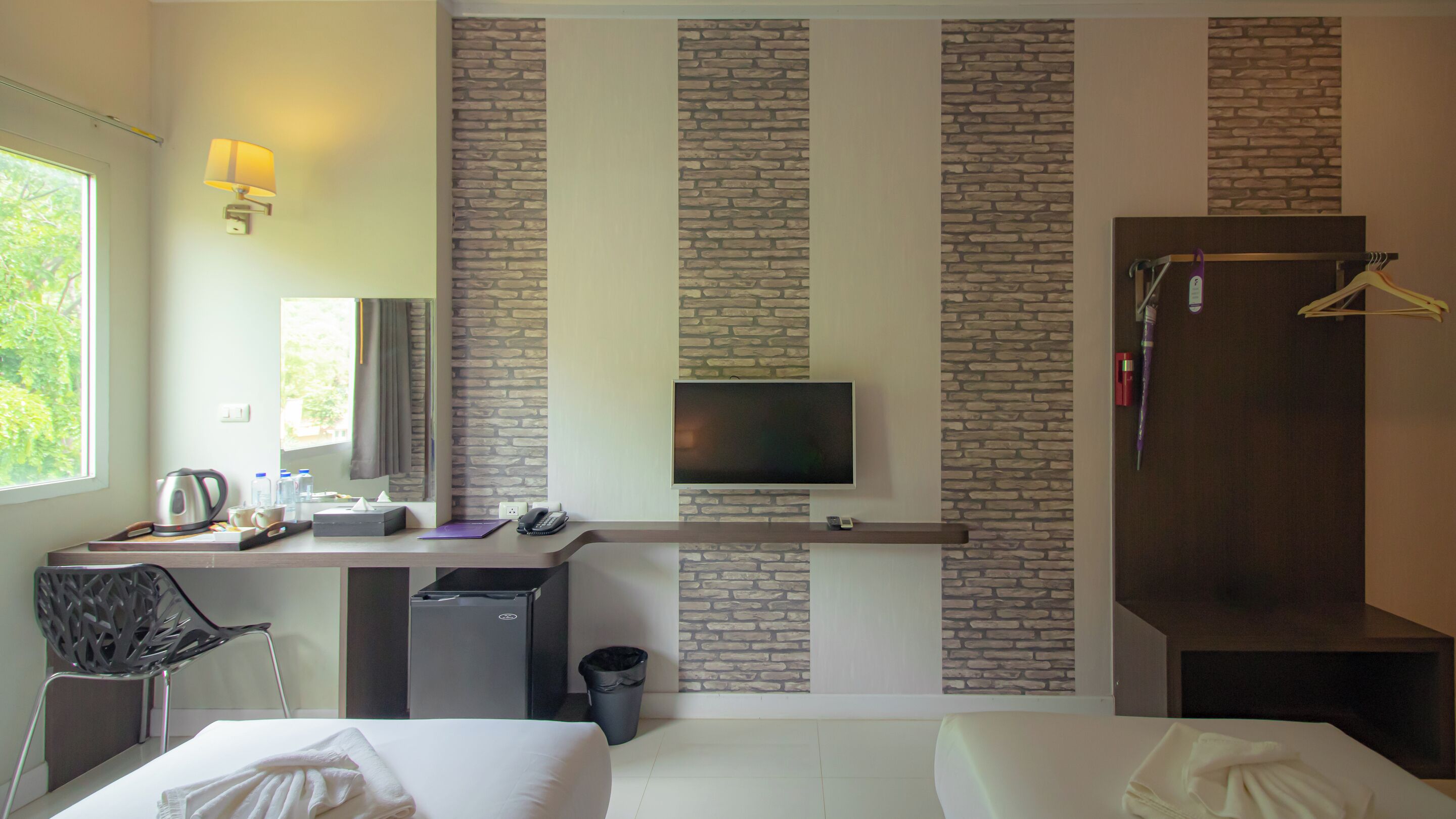 Una habitación de hotel con cama, escritorio con computadora, televisor y armario.