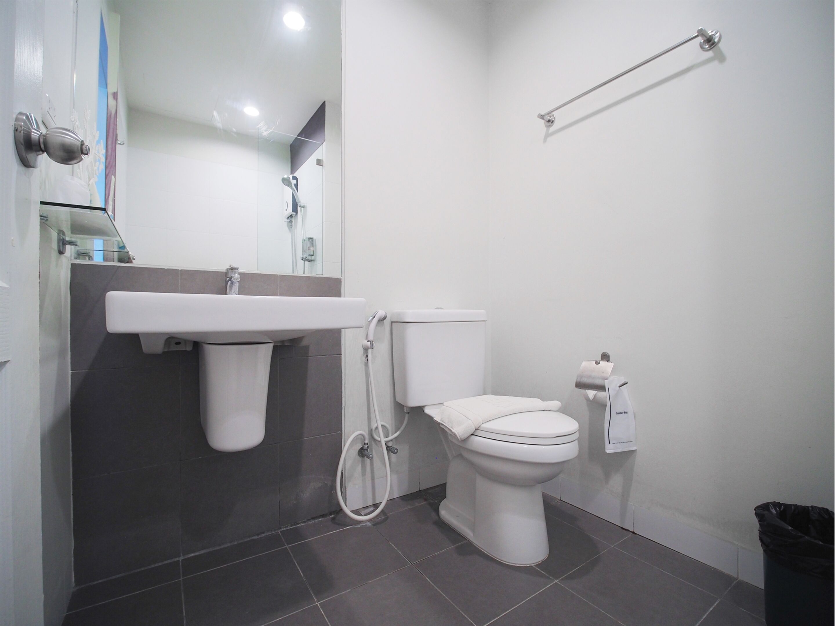 Un bany modern amb un lavabo blanc, vàter i una cabina de dutxa de vidre.