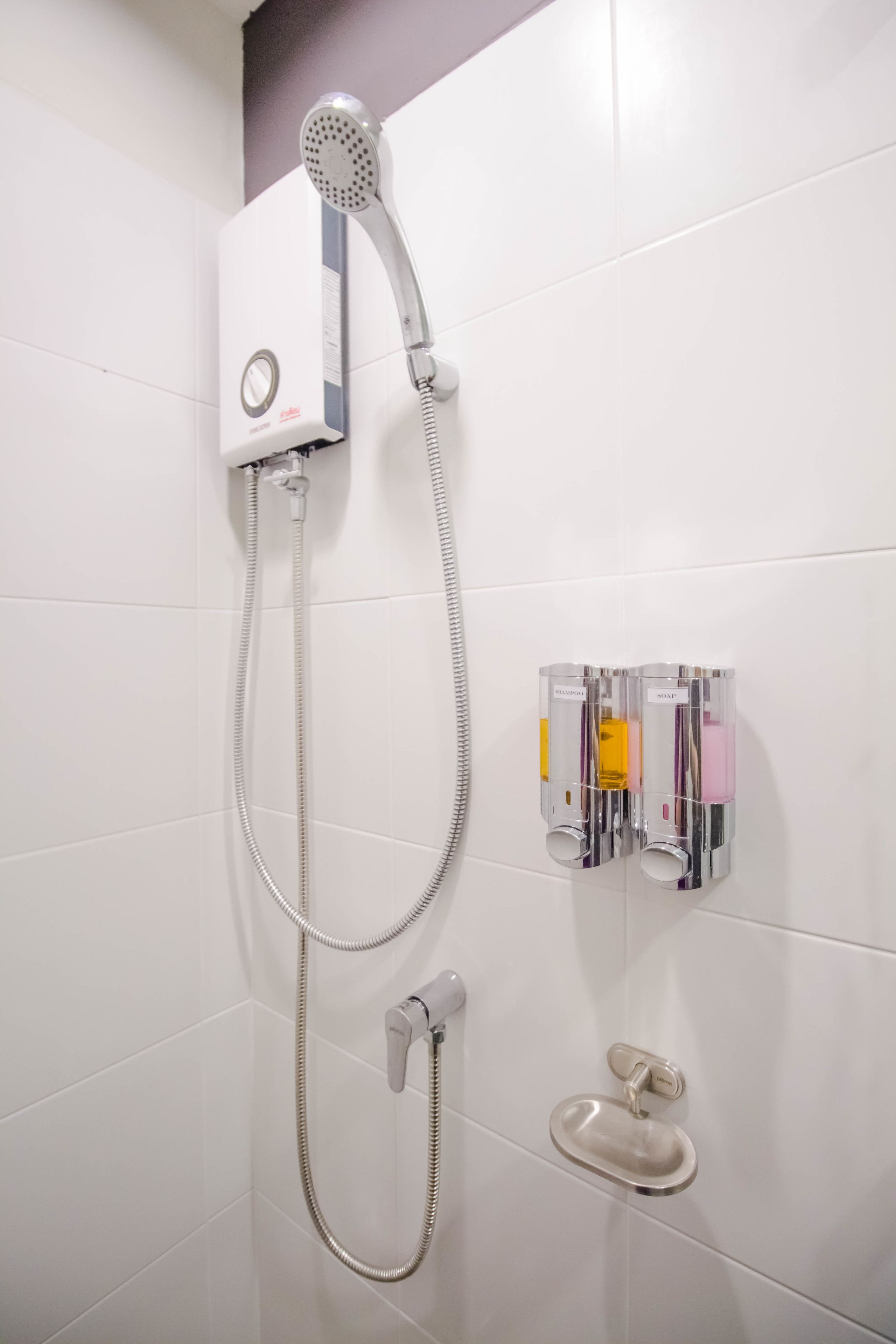 Eine Dusche mit Duschbrause, fest installierten Bedienelementen und einer separaten Handbrause.