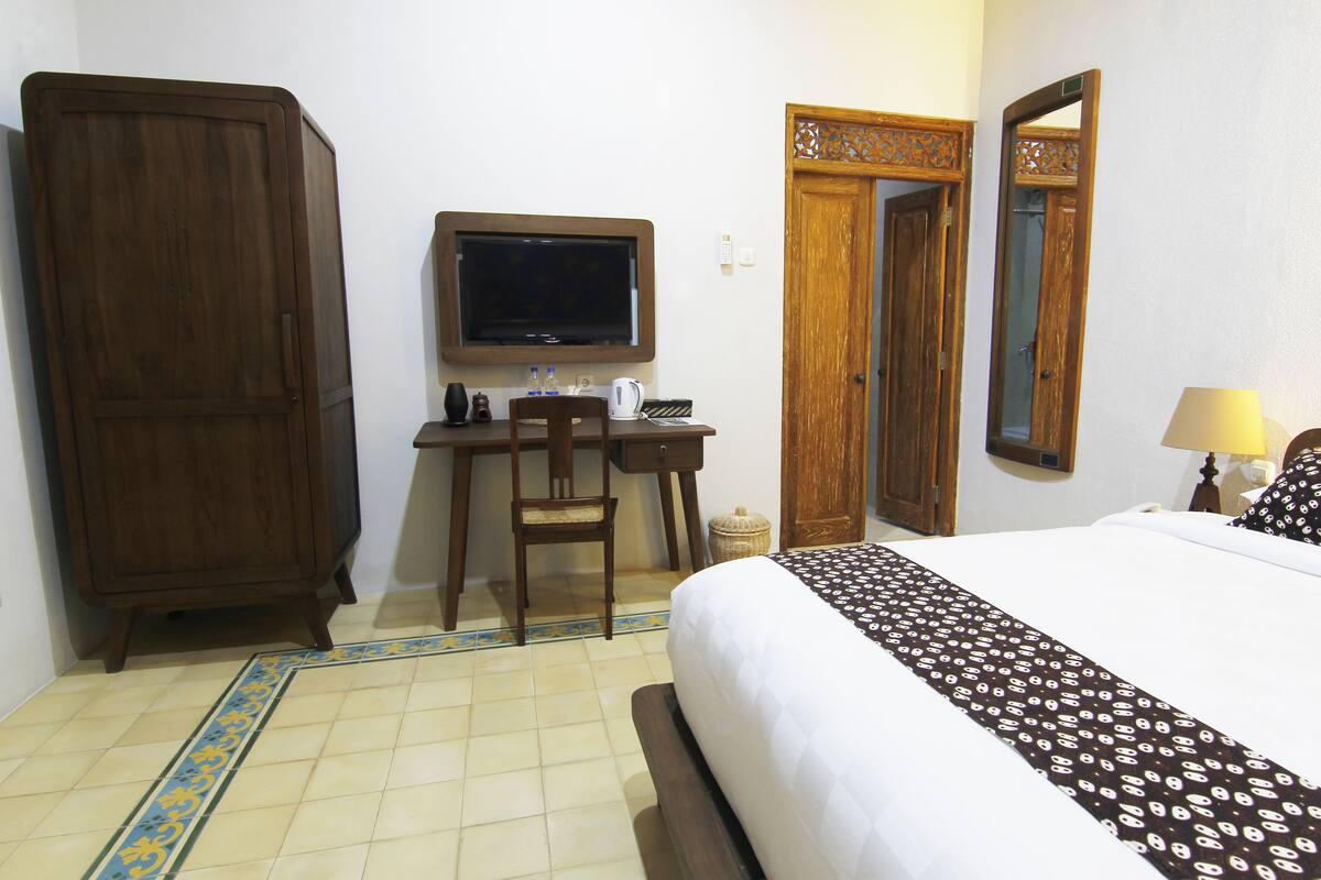 Une chambre à coucher comprenant un lit, un bureau avec une chaise, une télévision et une armoire.