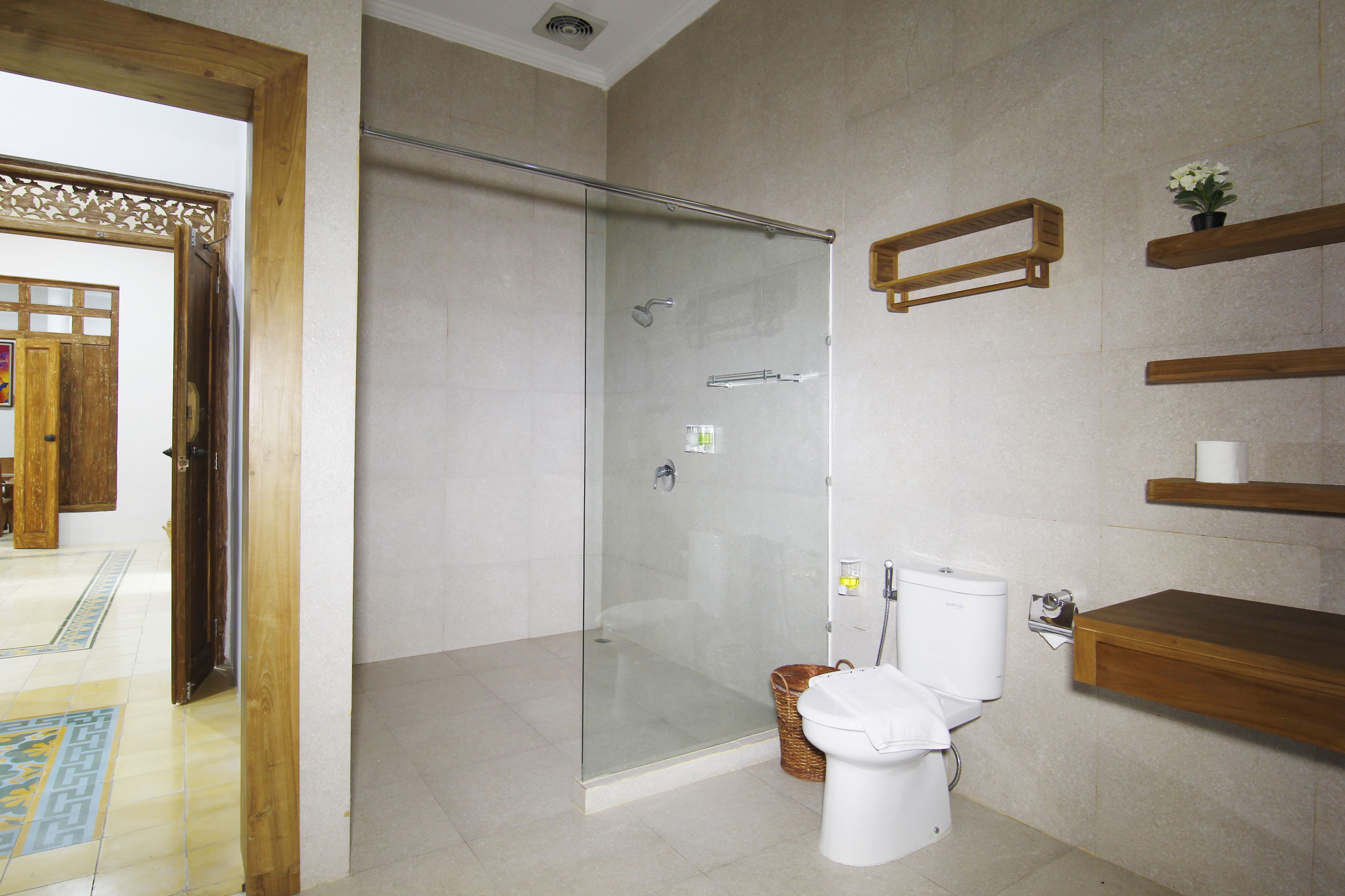 A modern bathroom with a glass-enclosed shower, a toilet, and wooden shelves.