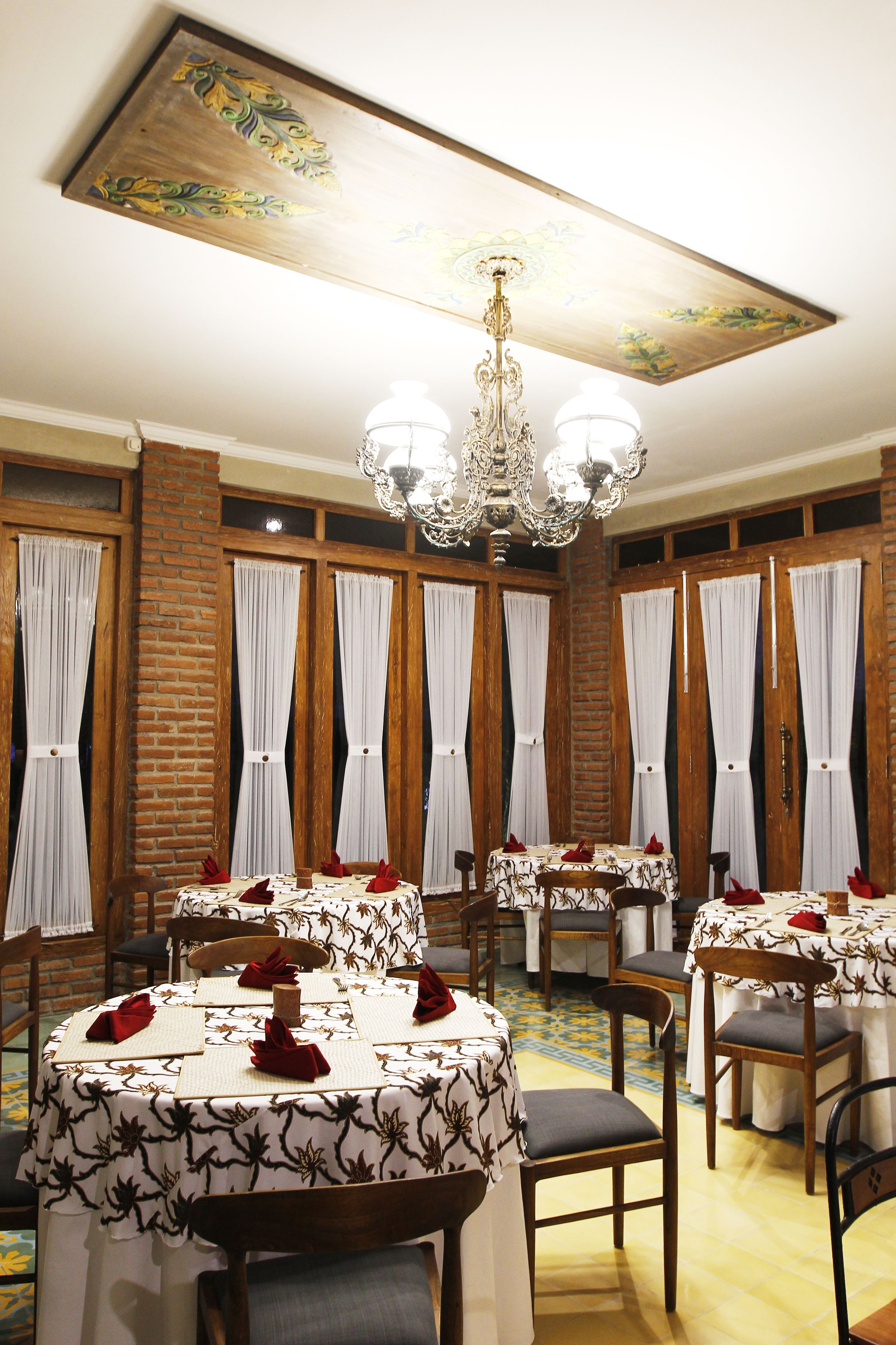 A dining area with round tables, chairs, and a chandelier.