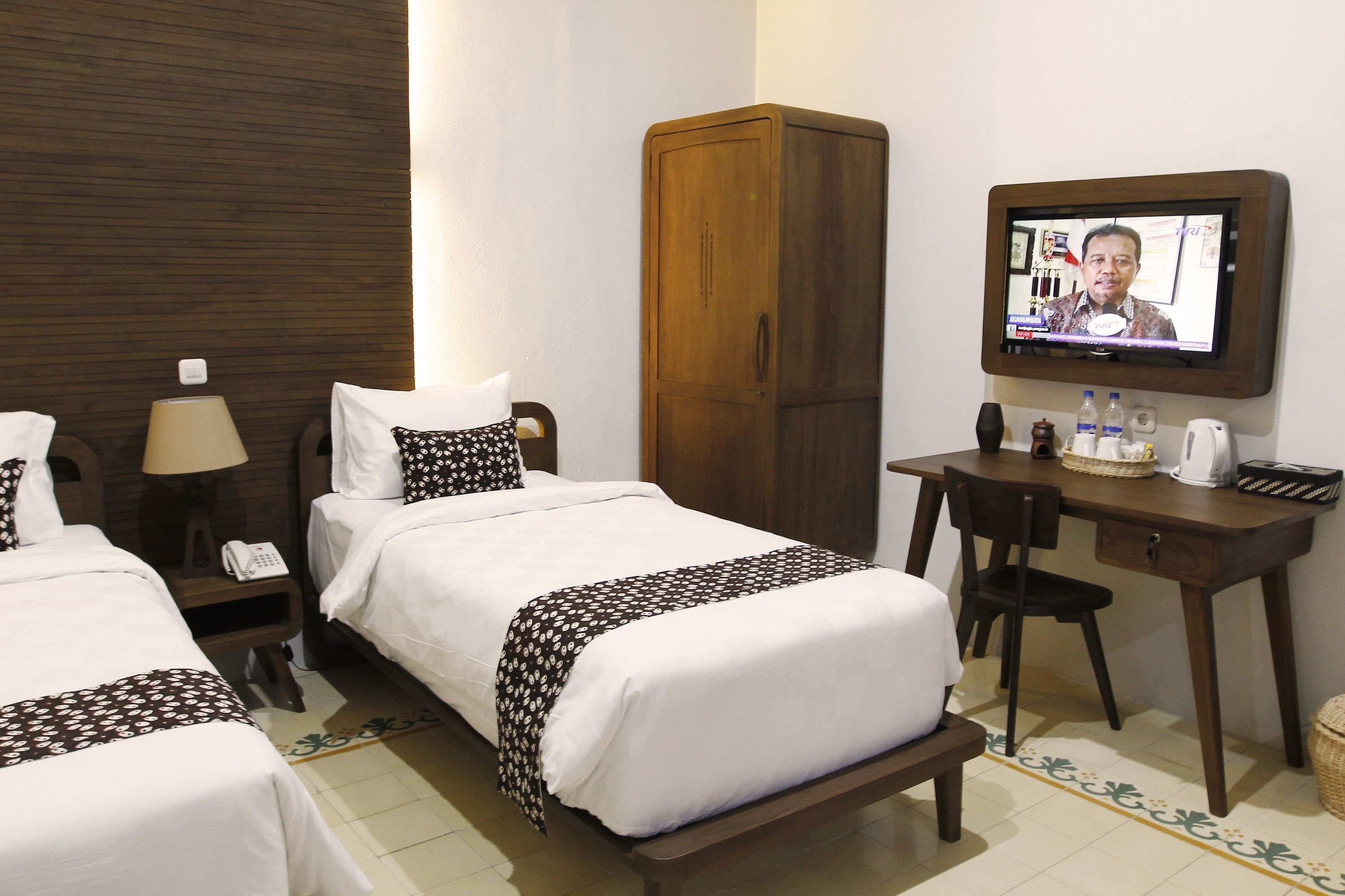 Une chambre d’hôtel avec deux lits, un bureau, une télévision et une armoire.