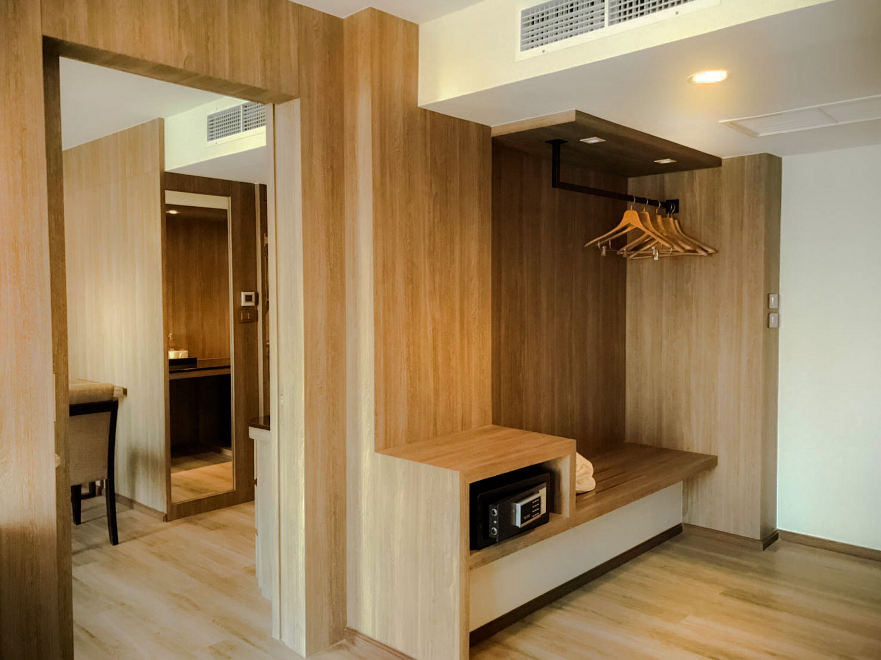 A modern room with wooden paneling, a built-in bench, a coat rack, and a small seating area.
