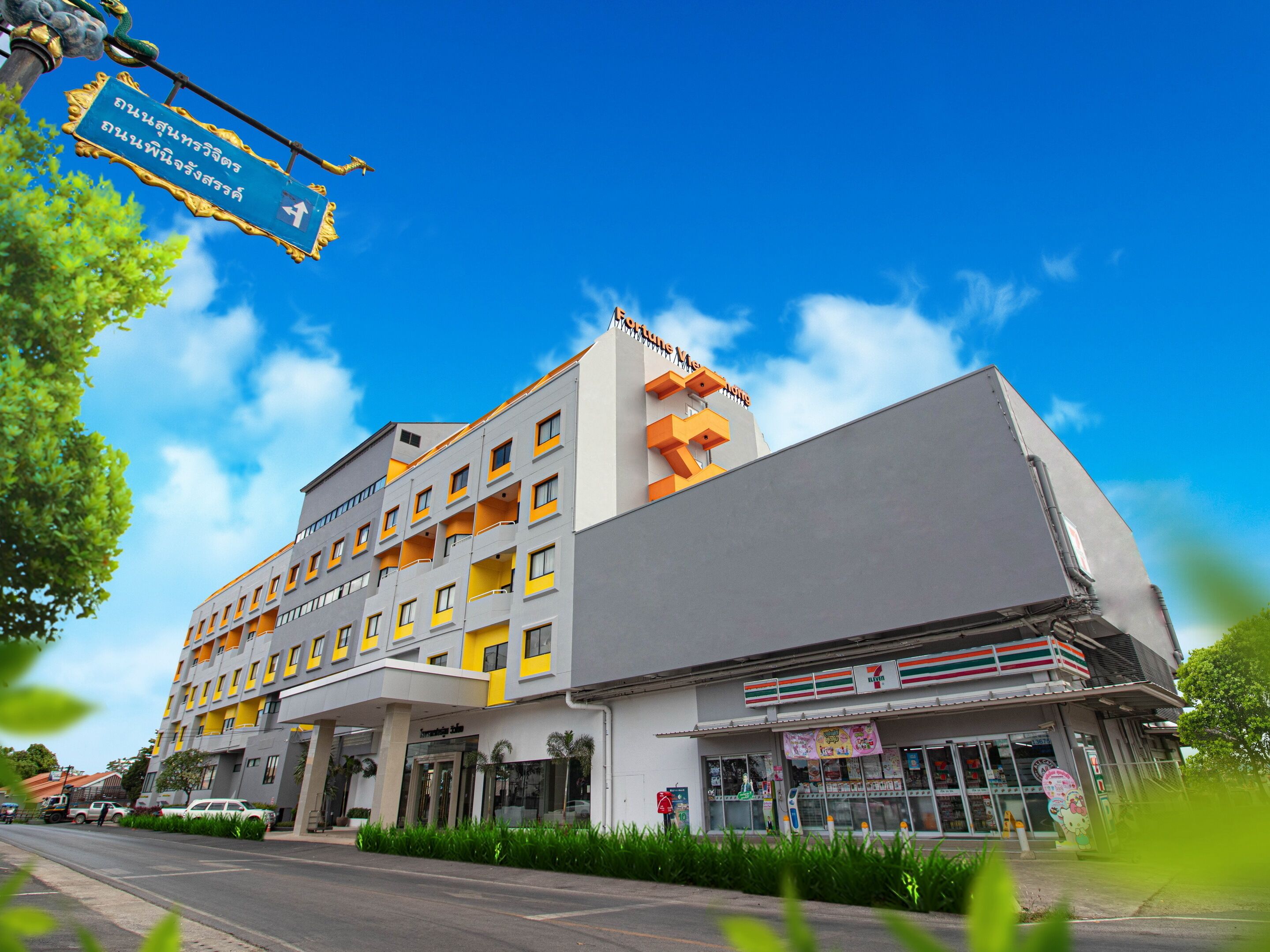 Een meerlaags hotel met een modern design, voorzien van balkons en een 7-Eleven winkel op de begane grond.