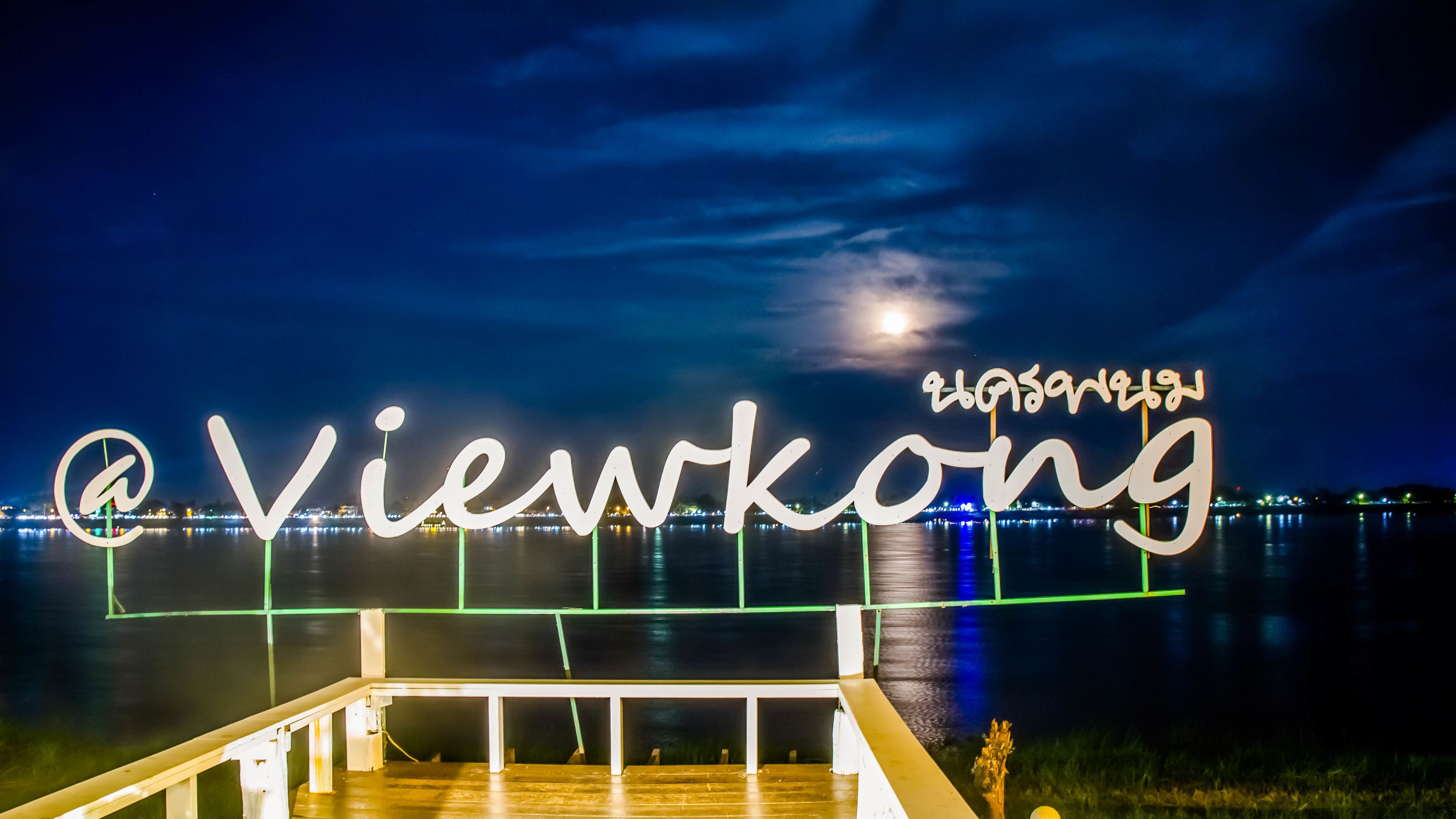 Une vue nocturne d’un front de mer, avec un texte illuminé affichant les mots « Viewkong » et « Viewkong ».