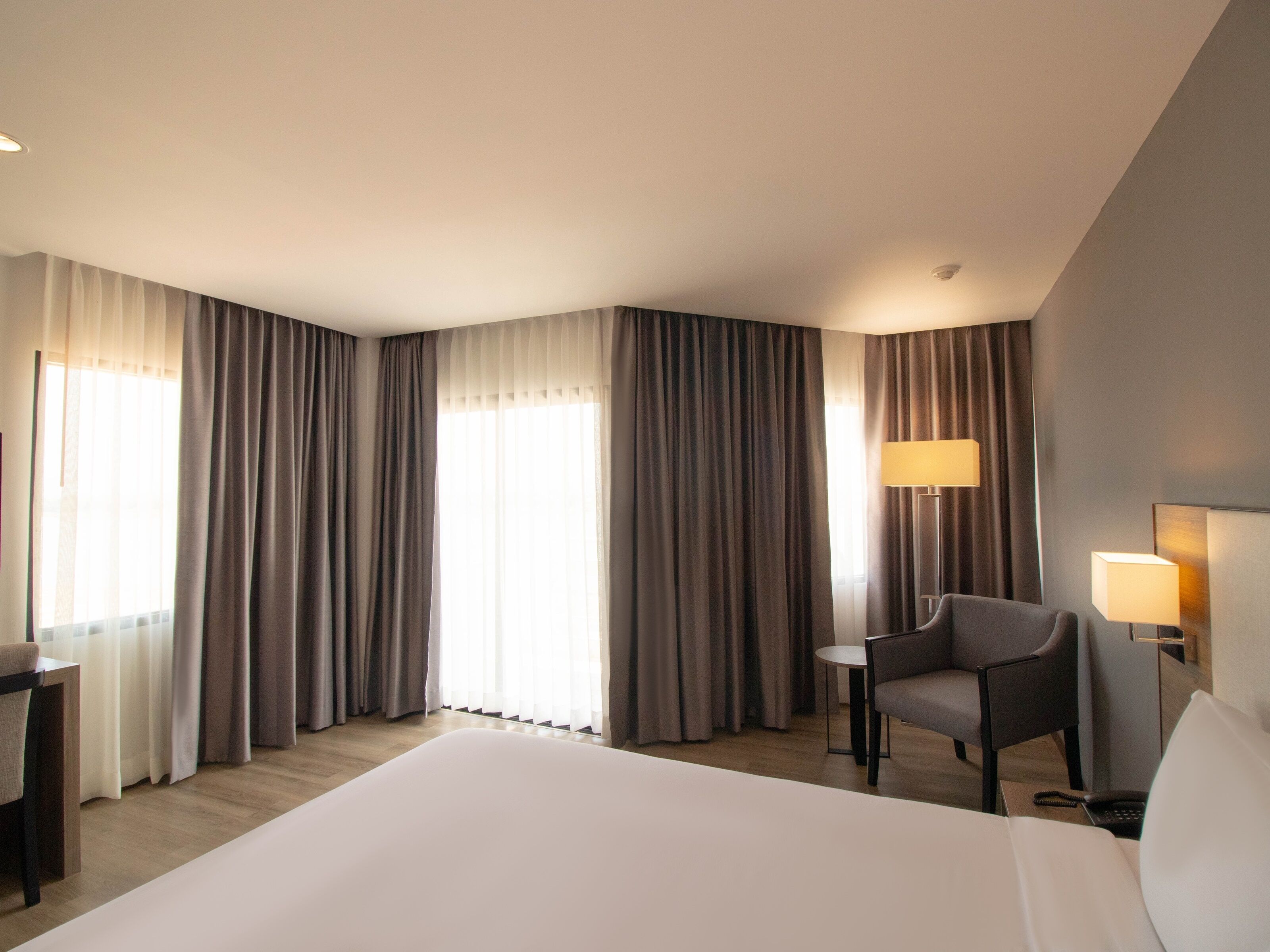 Una habitación de hotel con una cama grande, un escritorio, una silla y dos lámparas.