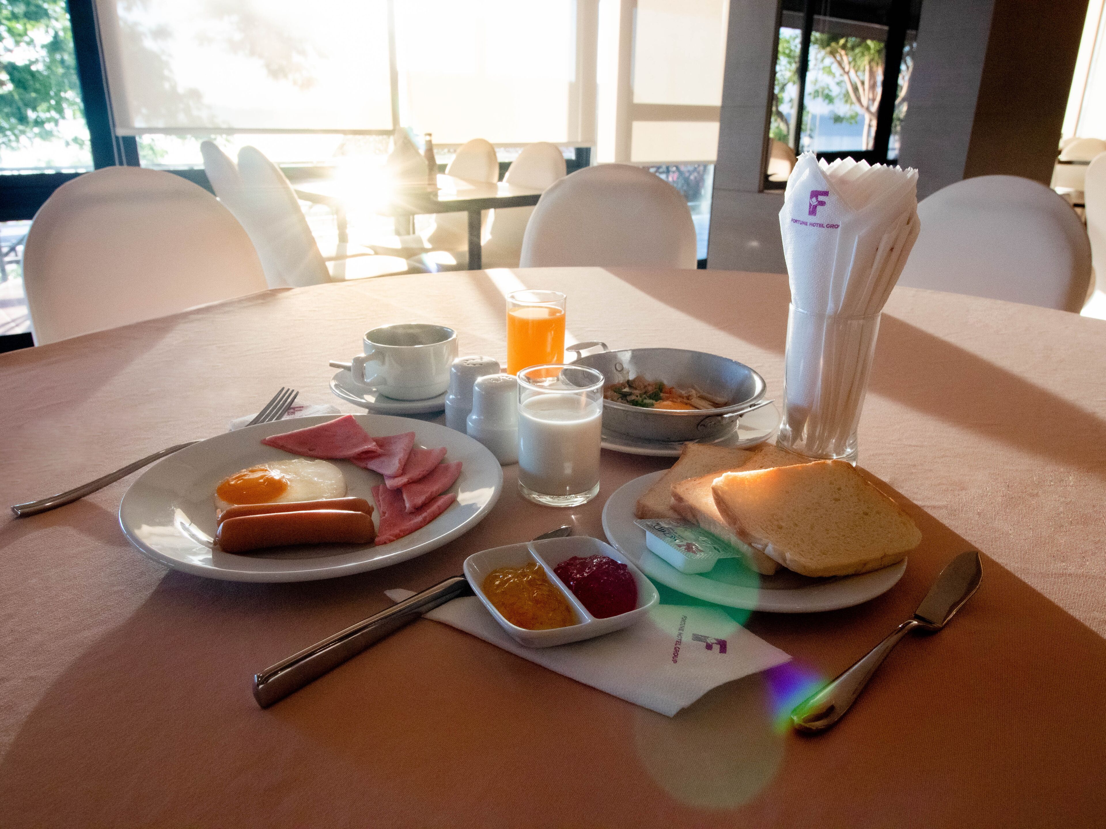Une table de petit-déjeuner avec des assiettes remplies de nourriture, des couverts et des condiments.