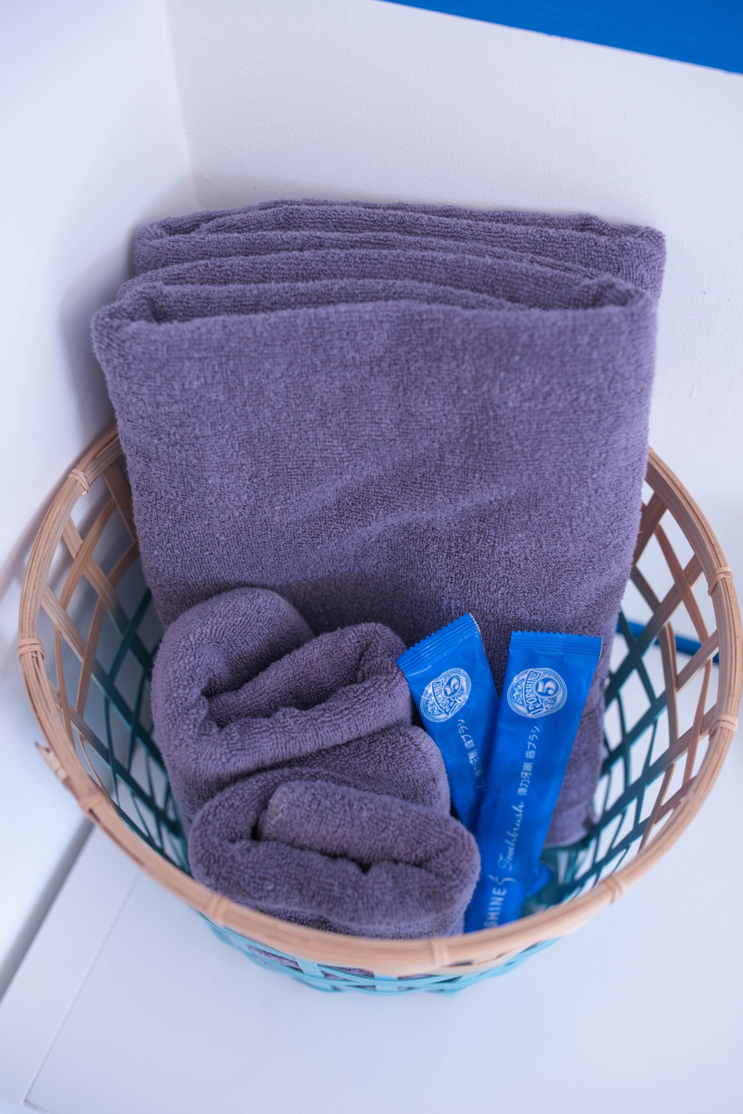A basket containing folded towels and two blue sachets.