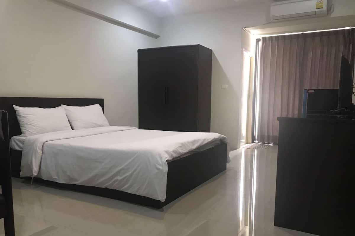 Quarto de hotel com cama, escrivaninha e guarda-roupa.