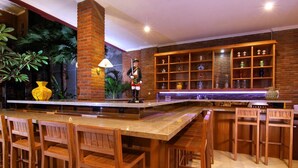 Eine Bar mit Holzsesseln, einer Theke und Regalen mit Dekoration.