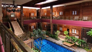 Ein mehrstöckiger Innenpoolbereich mit einem zentralen Pool, Holzbalkonen und einer Treppe.