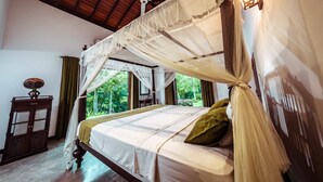 Una habitación con cama bajo dosel, un armario de madera y una ventana con cortinas.