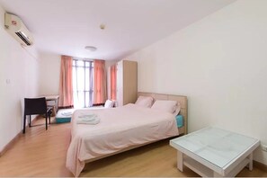 A bedroom with a bed, a desk, and a small table.