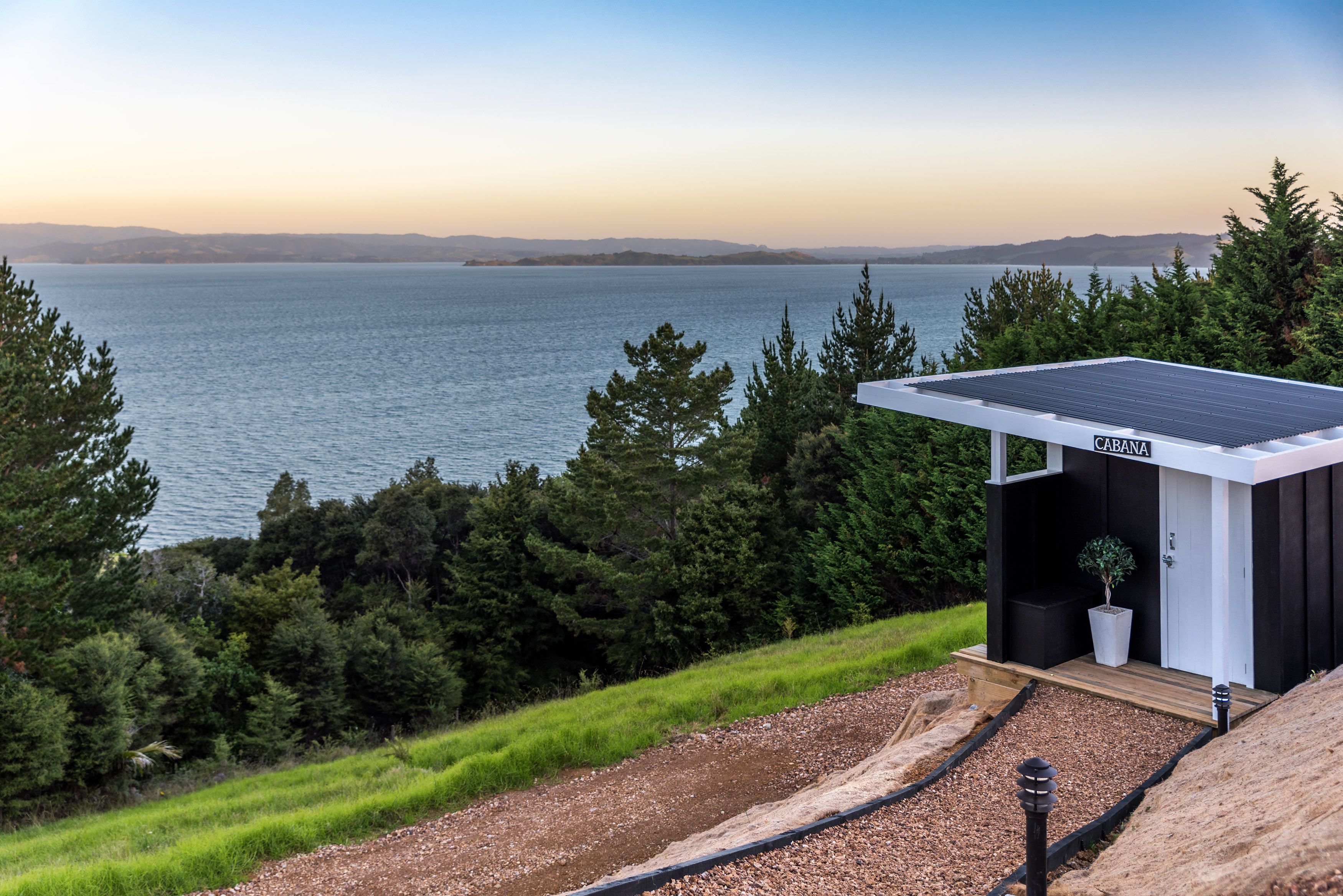A cabin with a solar panel roof overlooking a lake, surrounded by trees.