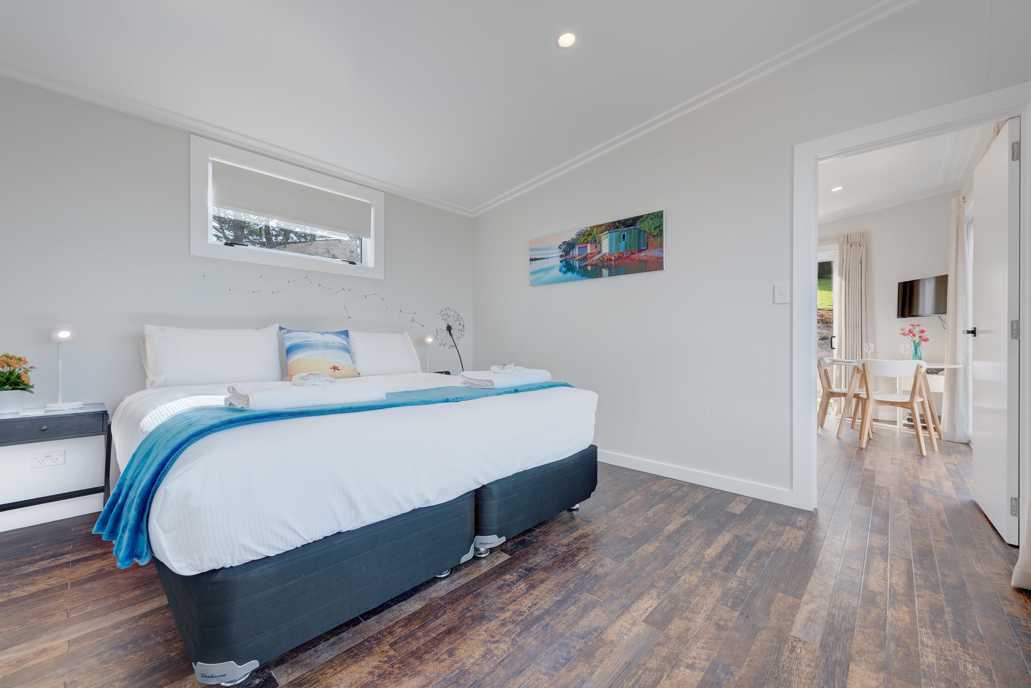 Un dormitorio con cama, mesita de noche y un cuadro en la pared.