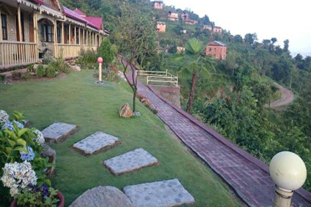A hillside property with a stone pathway leading to a building with a red roof.