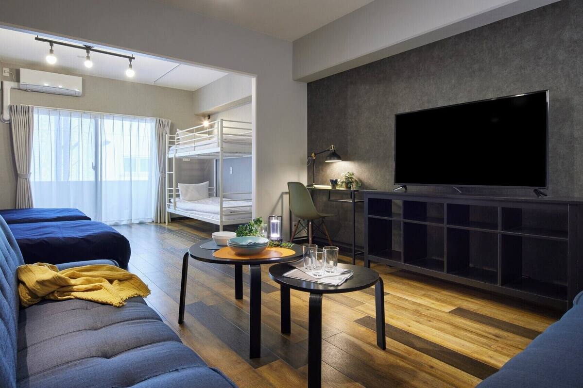 A modern living room with a sofa, a coffee table, a TV, and a bunk bed.