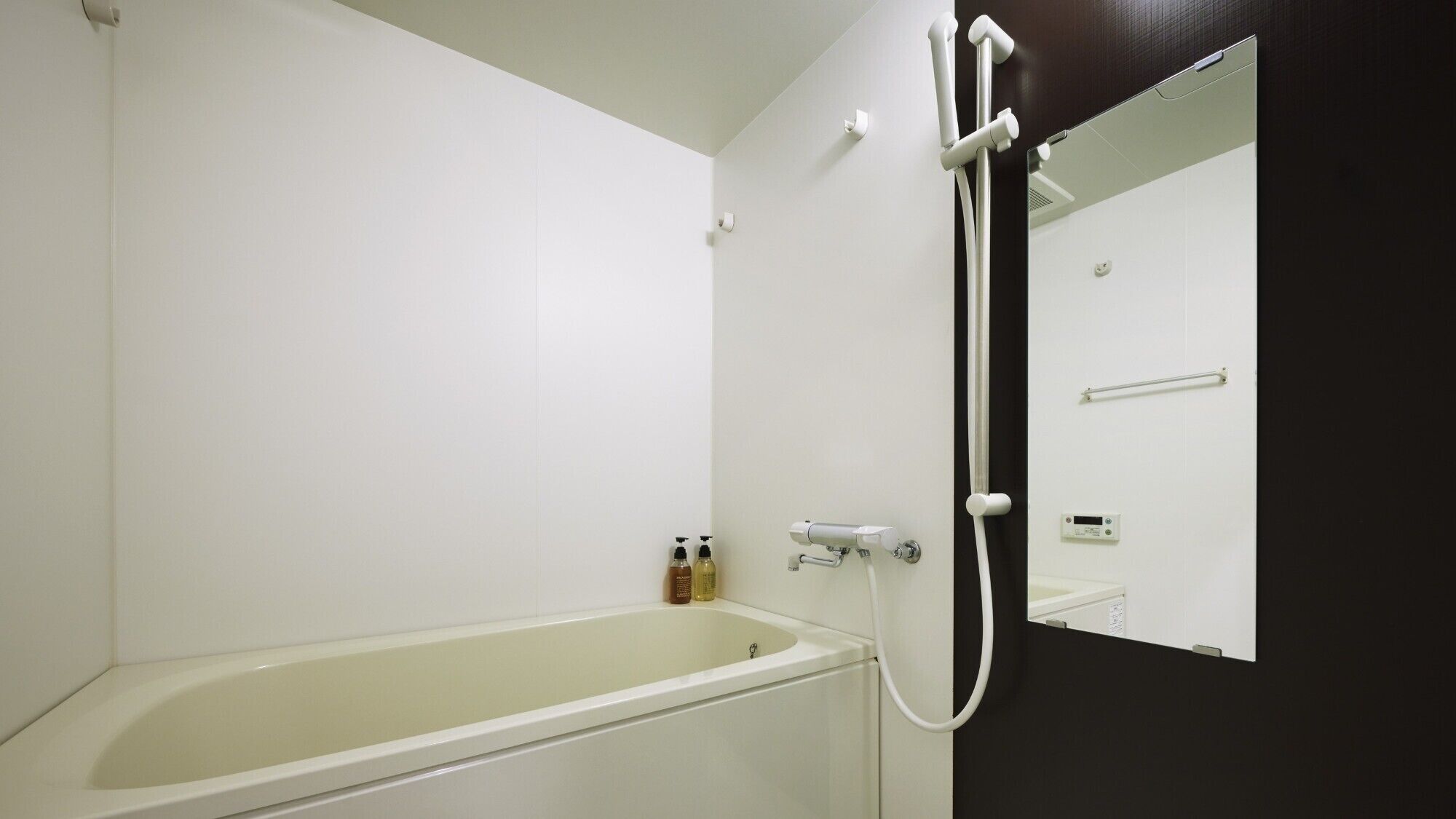 Un baño con bañera, ducha con cabezal de ducha manual y un espejo.
