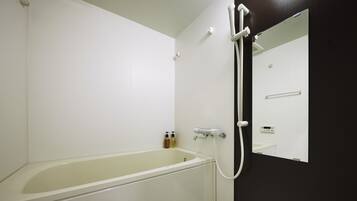 Un baño con bañera, ducha con cabezal de ducha manual y un espejo.