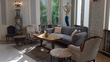 A spacious living room with a large grey sofa, two armchairs, a coffee table, and a decorative vase.