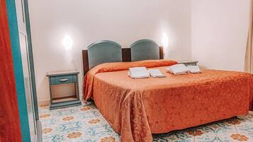 A hotel room with a bed, a nightstand, and a tiled floor.