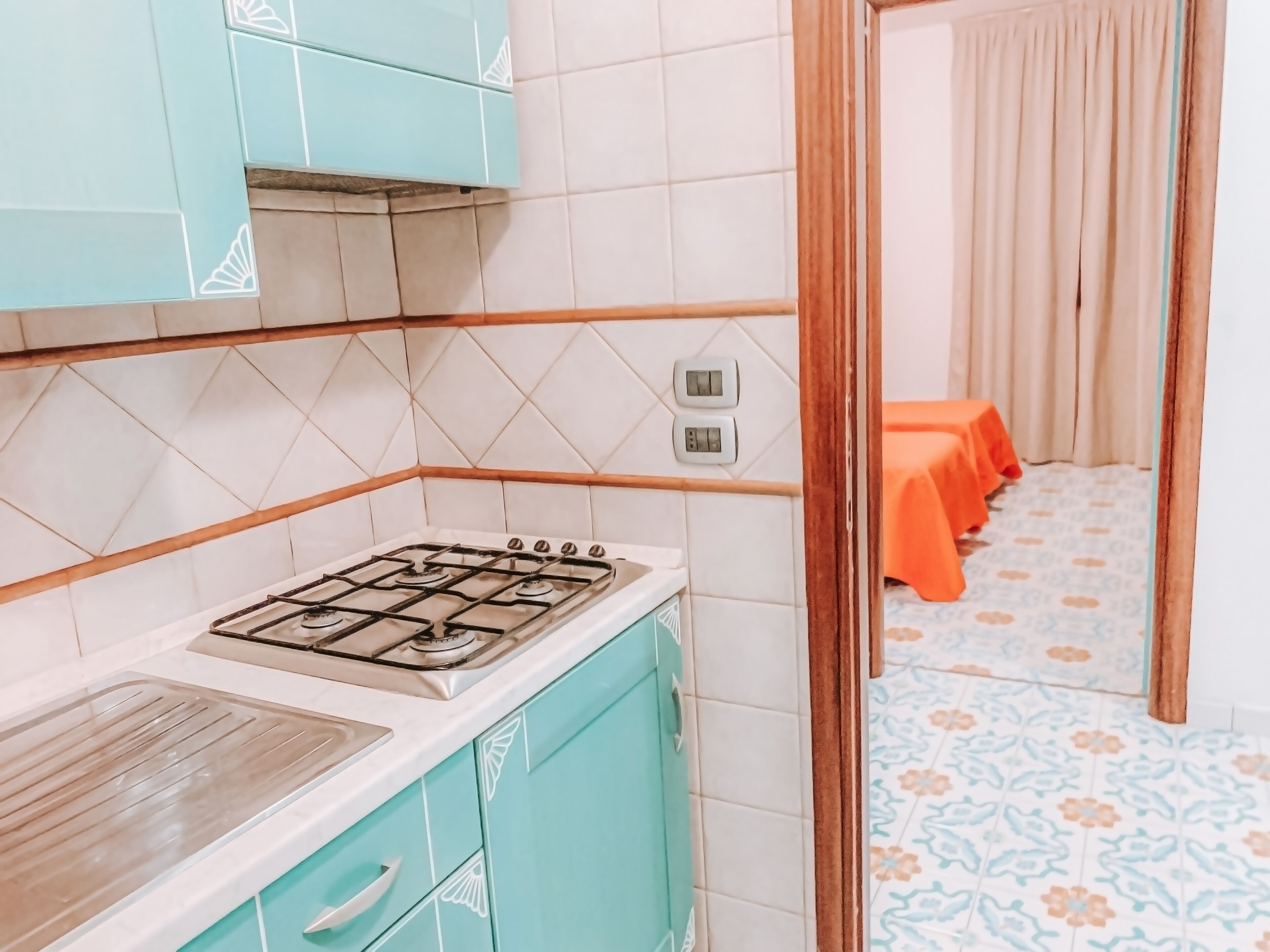 Une cuisine équipée d’une cuisinière à gaz, de placards et d’un crédence carrelée.