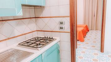 Une cuisine équipée d’une cuisinière à gaz, de placards et d’un crédence carrelée.