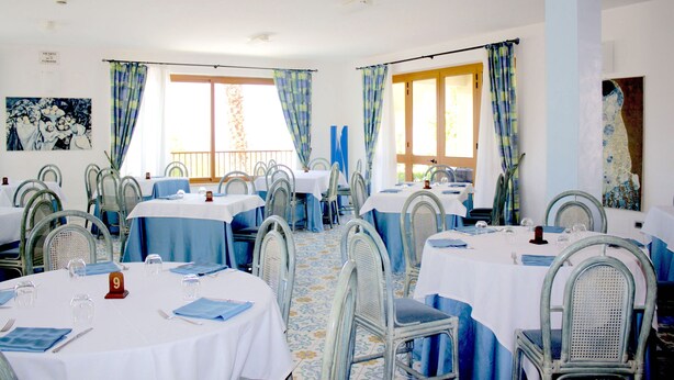 Un espace repas avec des tables rondes, des chaises et des nappes bleues.