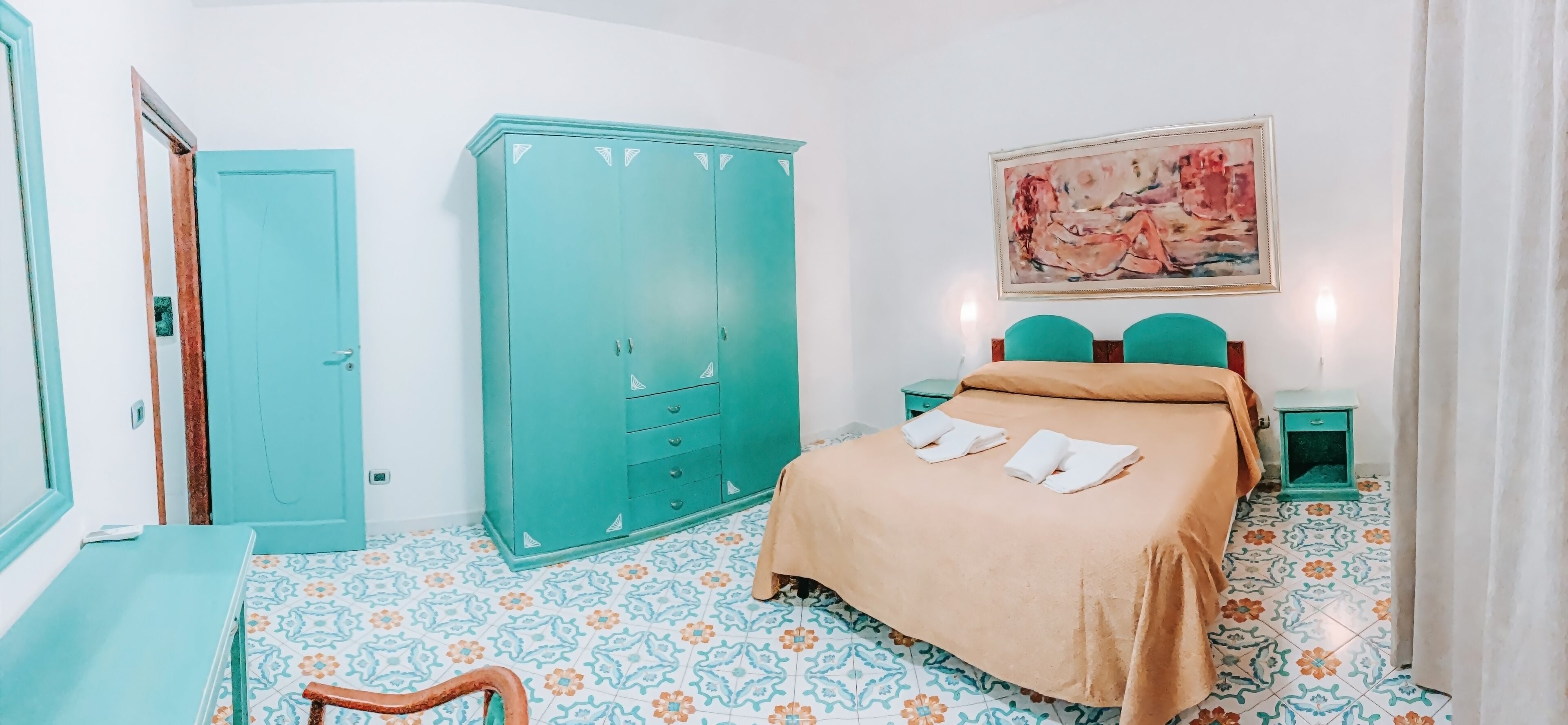 Una camera da letto con un letto, un armadio, un quadro e un tavolino.