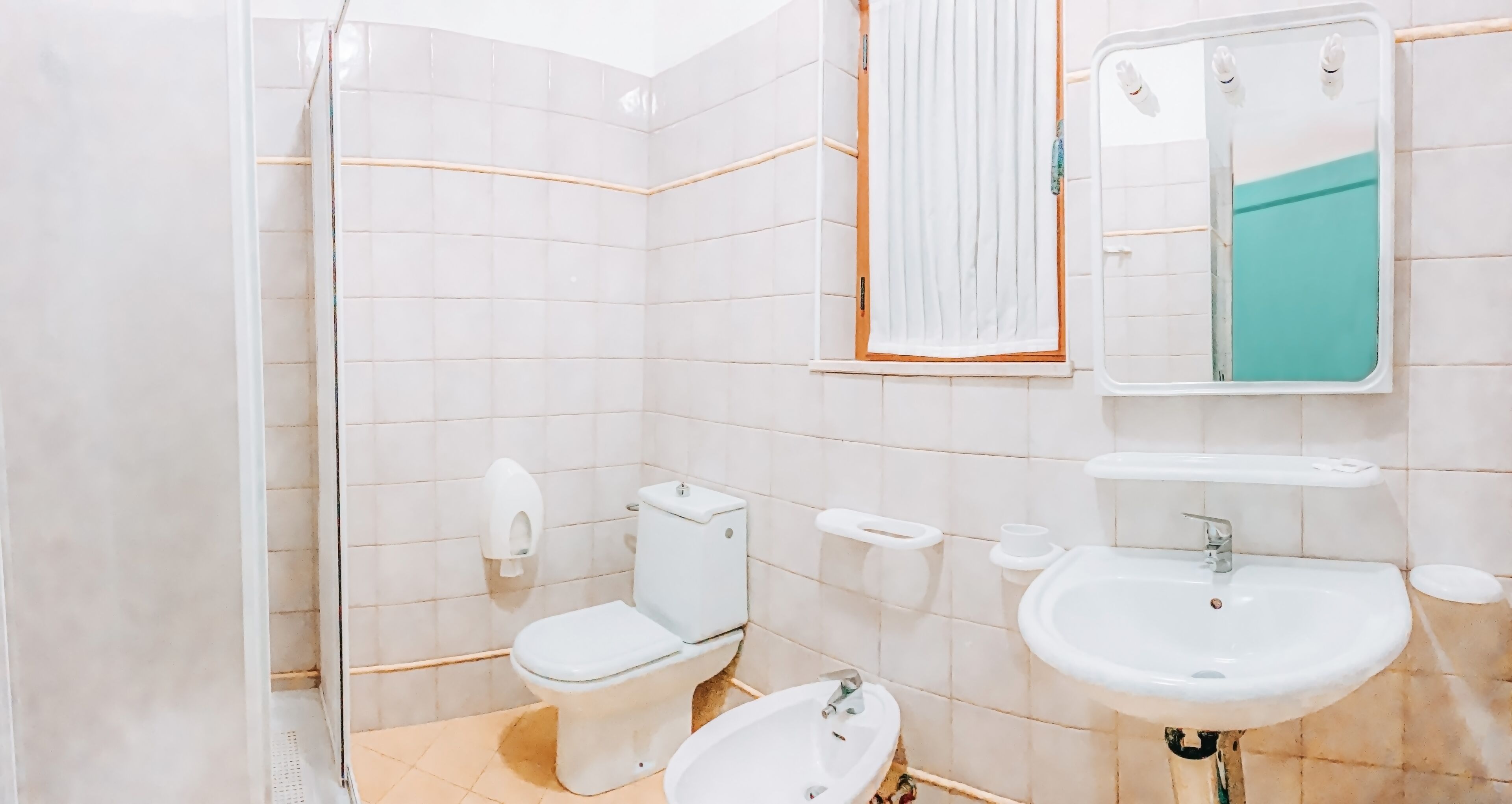 A bathroom with a toilet, bidet, sink, and mirror.