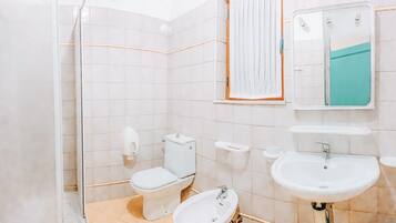 A bathroom with a toilet, bidet, sink, and mirror.