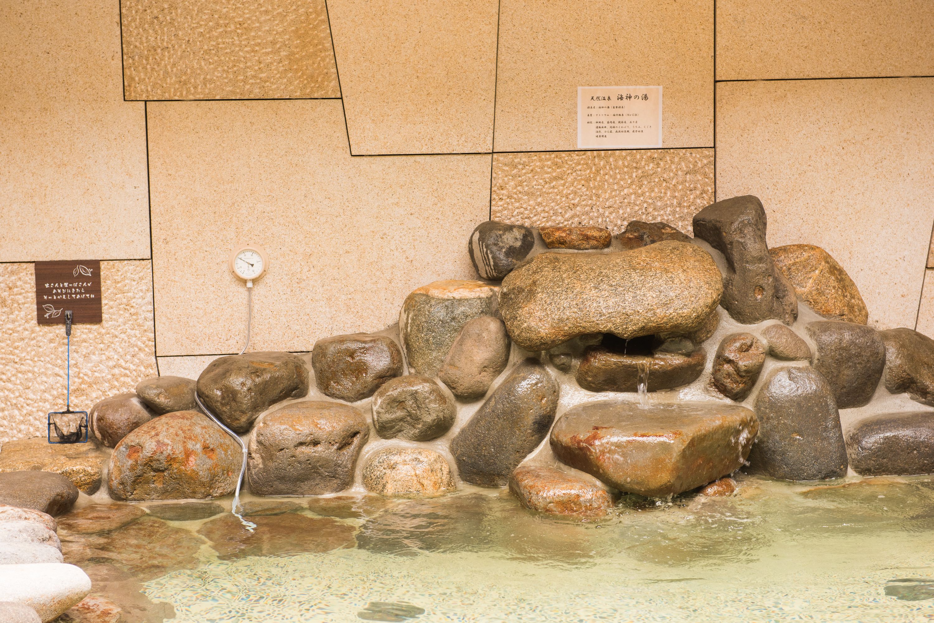A stone water feature with a clock and informational plaques.