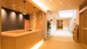 A modern reception area with a wooden reception desk, pendant lighting, and a staircase leading to an upper level.