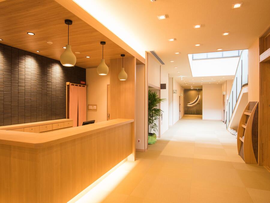 A modern reception area with a wooden reception desk, pendant lighting, and a staircase leading to an upper level.