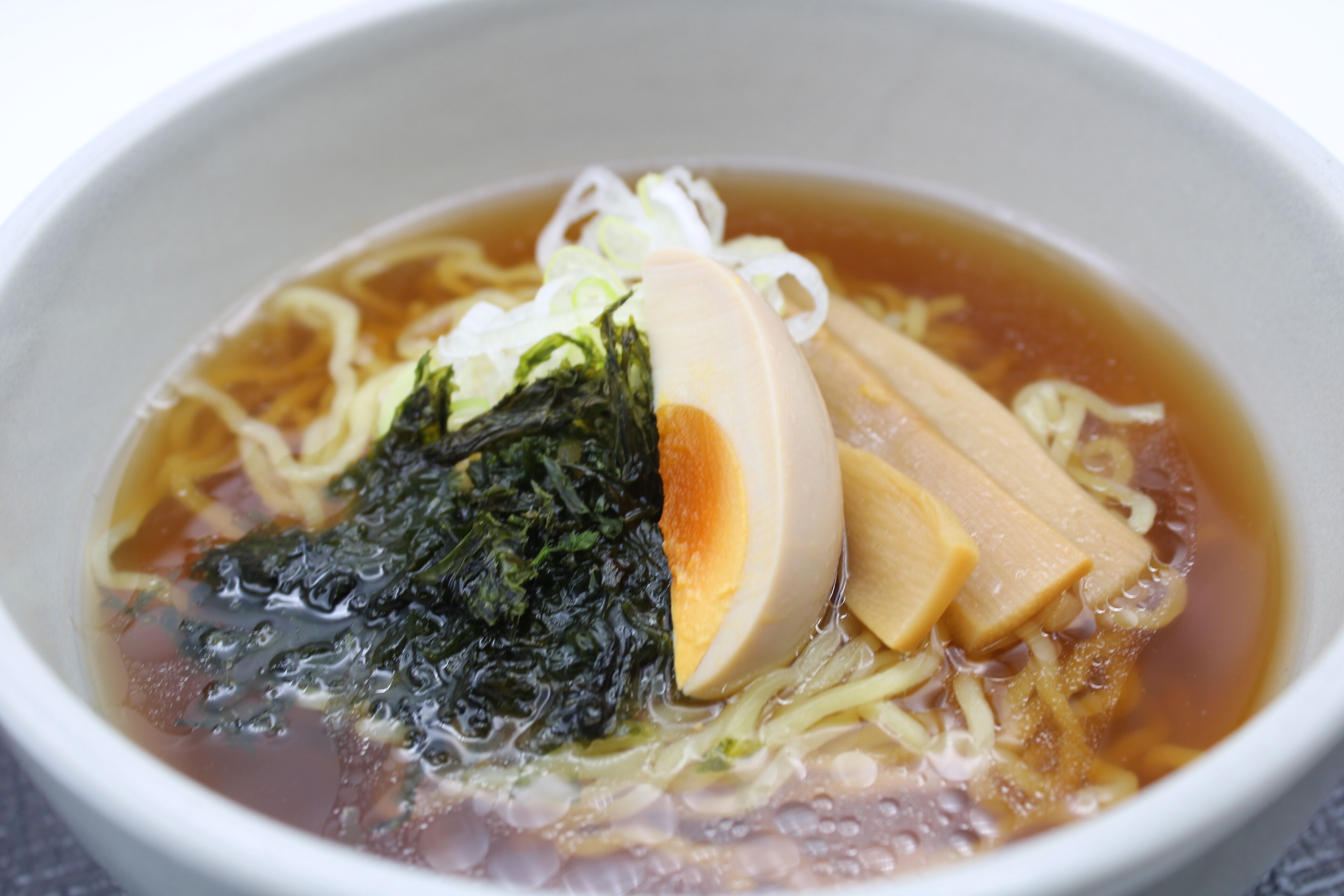 A bowl of ramen with noodles, seaweed, and slices of meat.