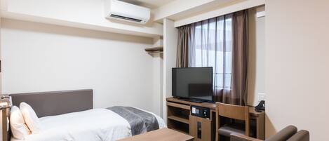 A hotel room with a bed, a desk, a television, and a sofa.