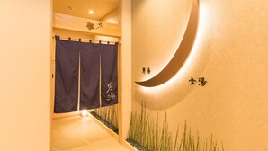 A corridor with a wooden ceiling, a wall-mounted crescent moon design, and a small indoor garden with bamboo.