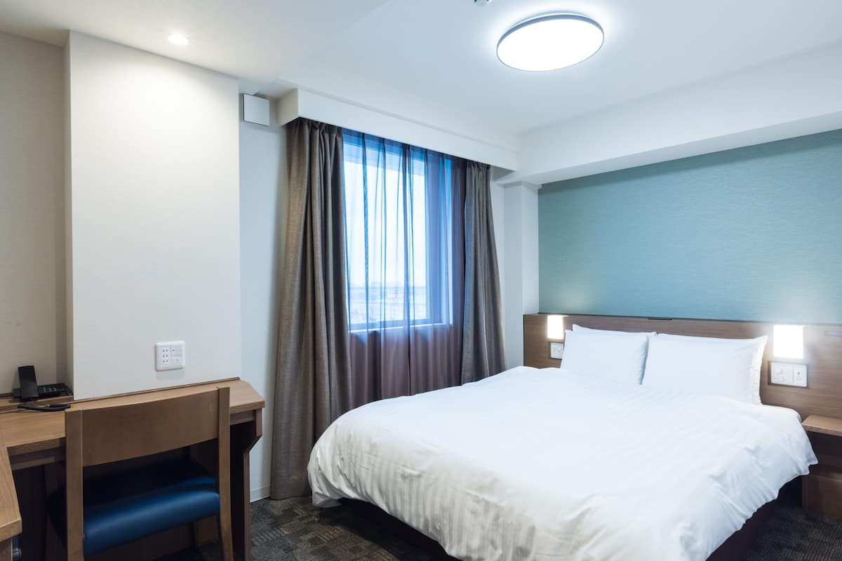 A hotel room with a bed, a desk, and a chair.
