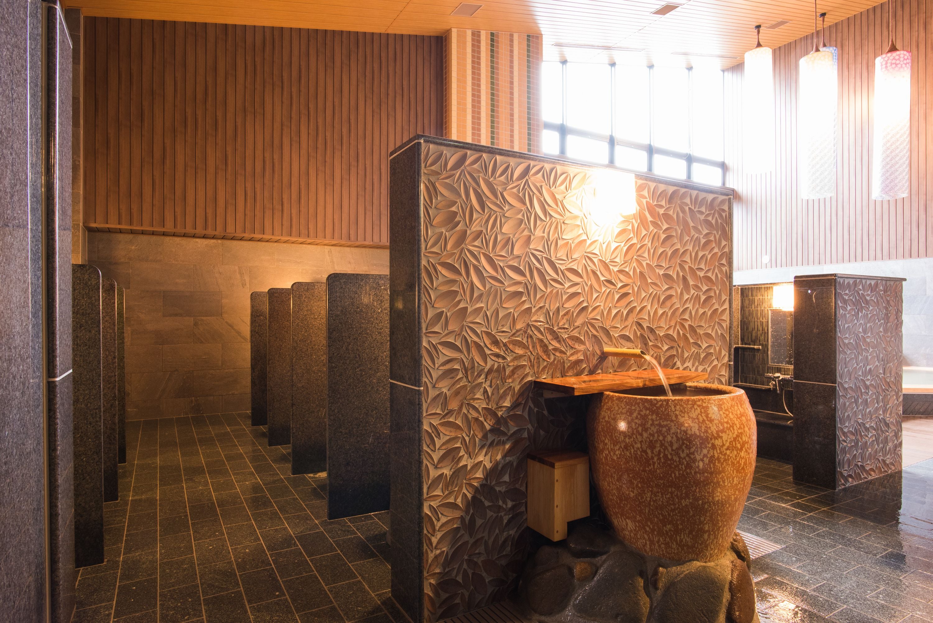 Un baño moderno con pared de piedra, pared con paneles de madera y un lavamanos de piedra grande.