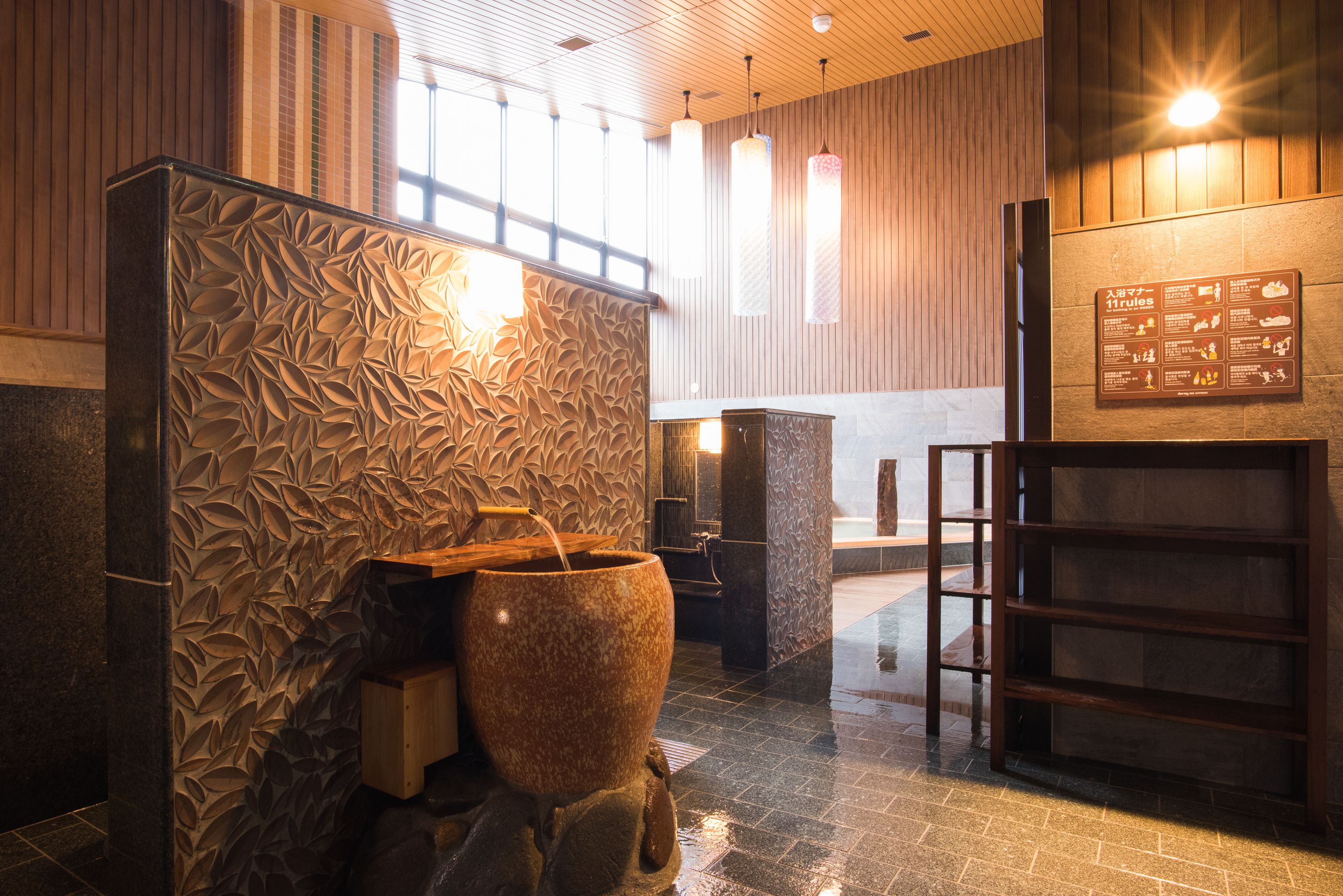 A spa area with a large stone basin, wooden paneling, and a sign with rules.