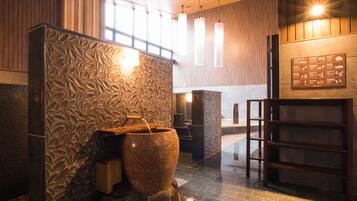 A spa area with a large stone basin, wooden paneling, and a sign with rules.