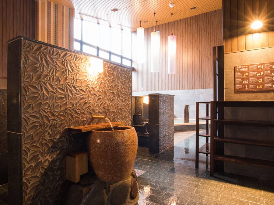A spa area with a large stone basin, wooden paneling, and a sign with rules.