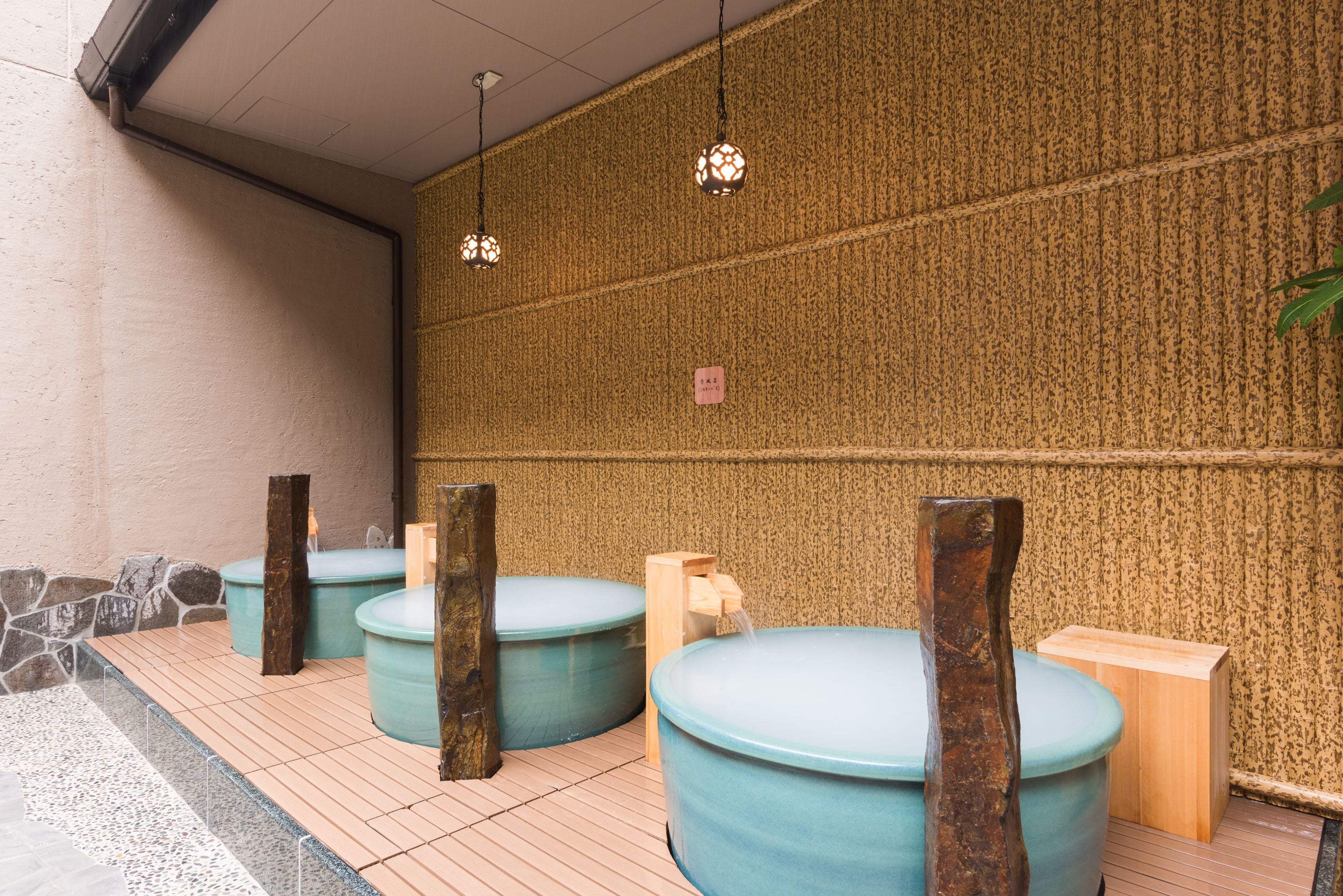 A traditional Japanese onsen with multiple hot tubs and wooden stools.