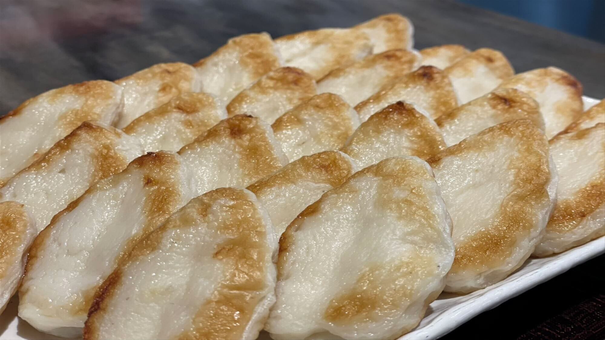 Un vassoio di ravioli al vapore con una crosta dorata.