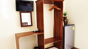 A compact room with a wooden console table, a small refrigerator, a television mounted on the wall, and a potted plant. - Baan Maesot Boutique Resort (Mae Sot)
