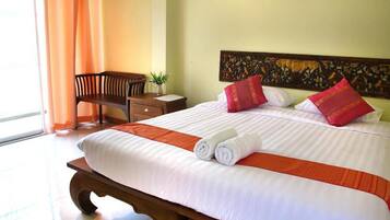 A hotel room with a large bed, a wooden nightstand, a chair, and a window with curtains.
